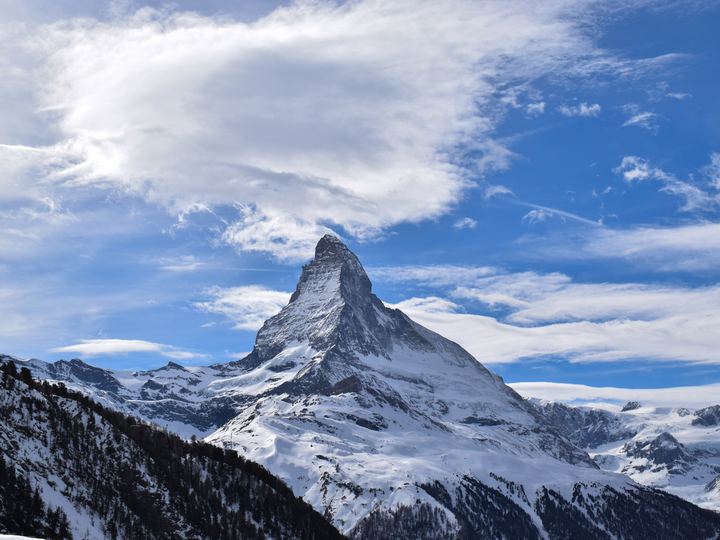 The snow-covered pyramid of the Matterhorn against a clear blue sky