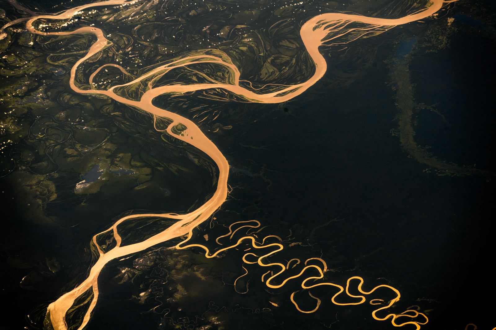 Aerial view of the wide brown Amazon River curving through green rainforest